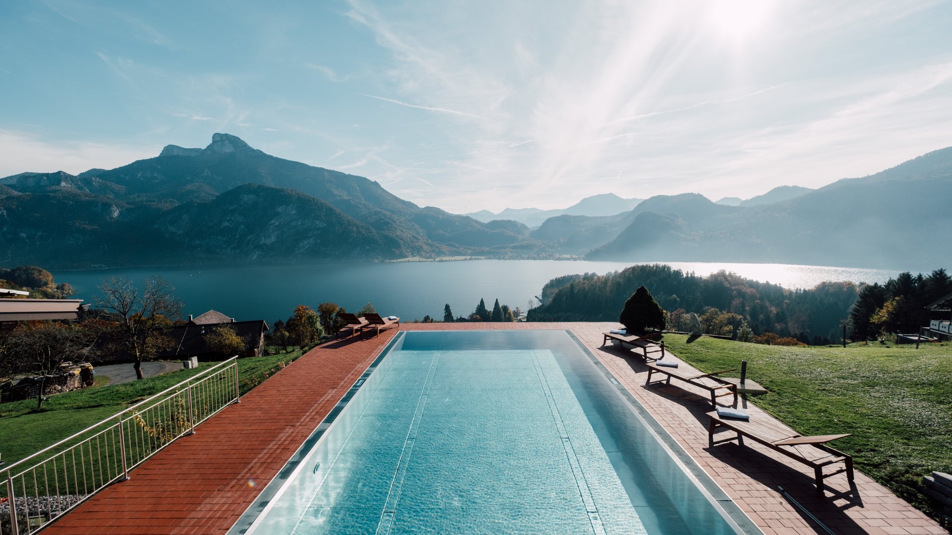 Entspannung am Pool mit Bergblick Schwimmingpool mit Blick auf einen See und Berge, Liegestühle in der Nähe arrangiert.